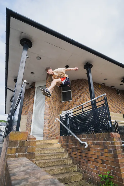 Arthur Gledhill-Franks performing a precision jump off a rooftop ledge